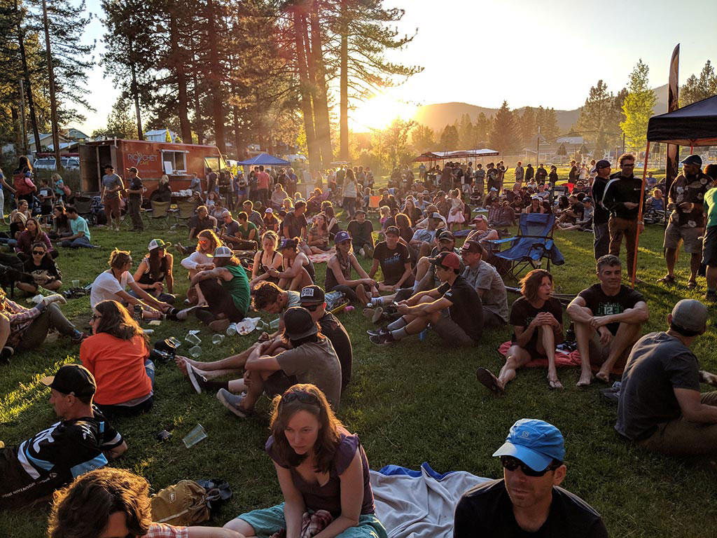 Crowd sitting on grass in a park with a festival atmosphere